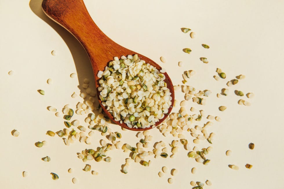 wooden spoon with purified and ground hemp seeds on beige background