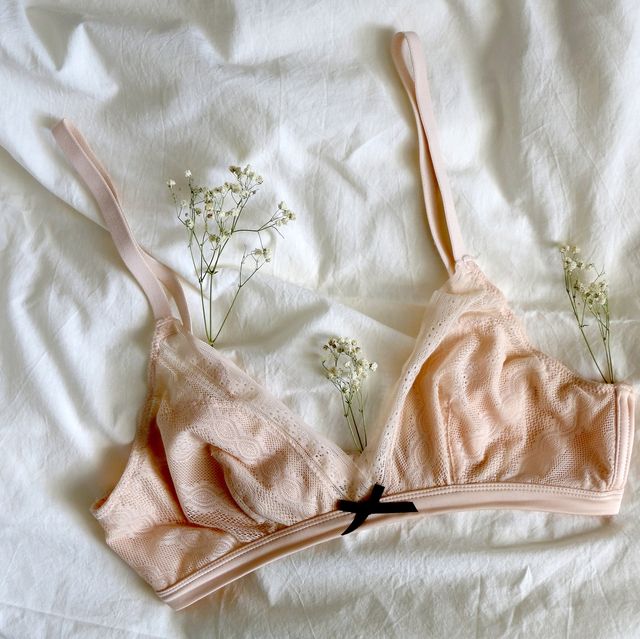 pale pink bralette and gypsophila flowers on white sheets top view