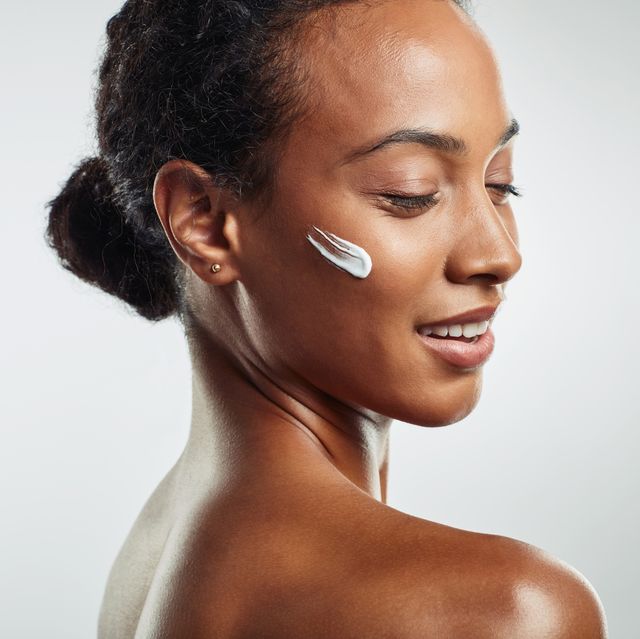 black woman with beautiful skin, eyes closed, with streak of face mask product on cheek