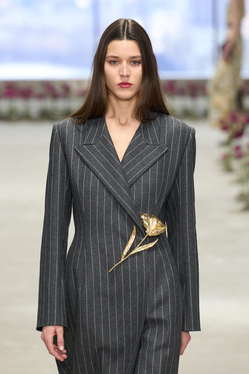 fashion model wearing a gray pinstripe suit with a floral embellishment