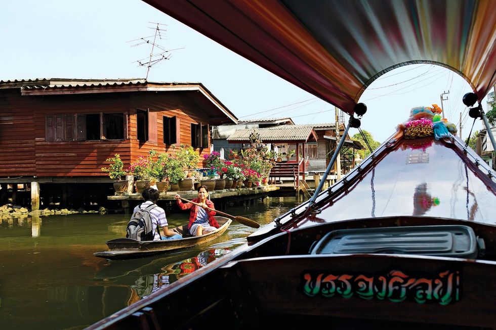 Boten varen langs paalwoningen aan het Bangkok Noikanaal een van de vele waterwegen die de stad doorkruisen