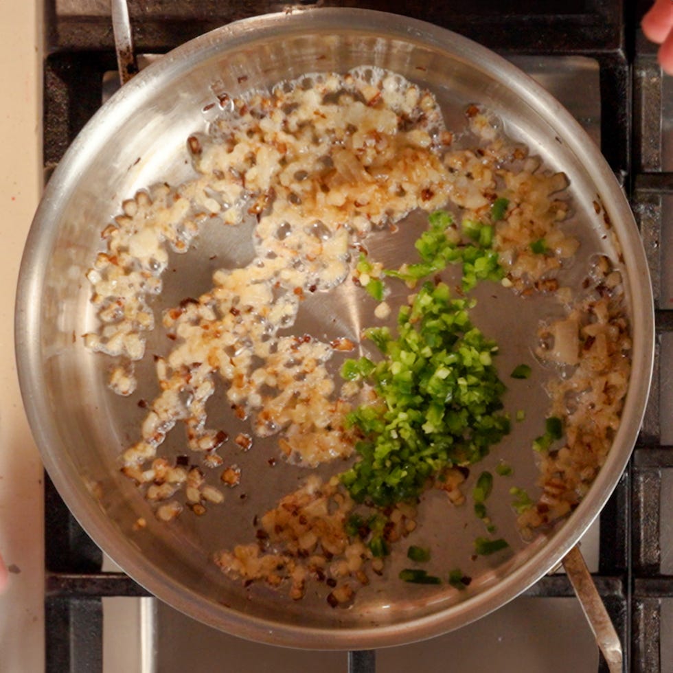 a mixture of onions garli, and jalapenos cooking in a skillet
