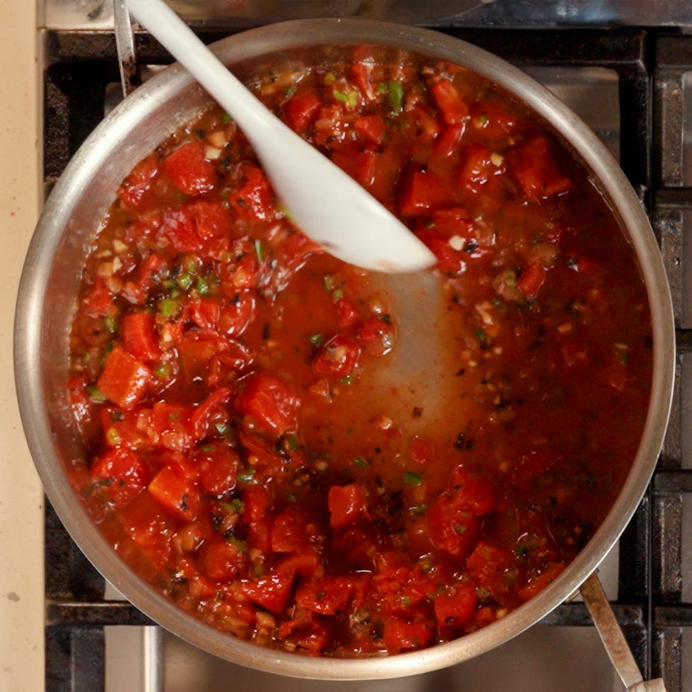cooking a tomato based sauce with diced tomatoes and onions in a skillet
