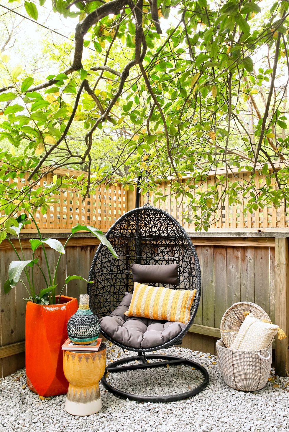 hanging black seat with yellow stool and big red planter next to it