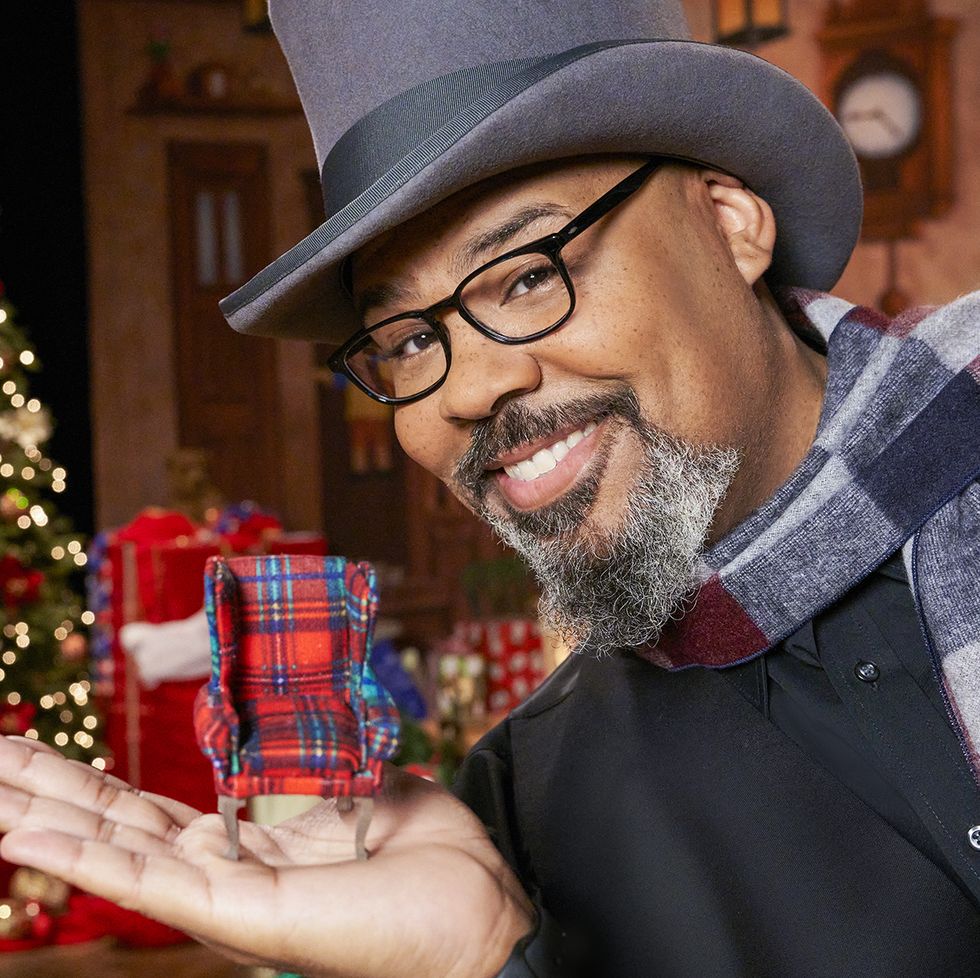 host james monroe iglehart holds a tiny armchair from one of the contestant's challenge homes, as seen on the biggest little christmas showdown portrait