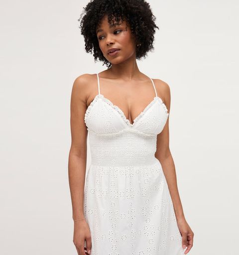 a black woman with curly hair in a white smocked summer dress