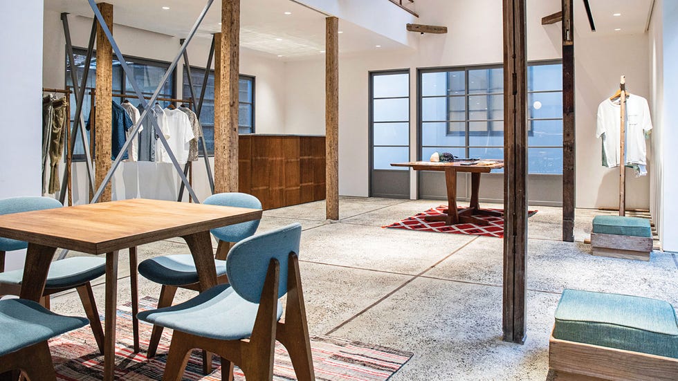 a modern retail space with a wooden table and clothing displays