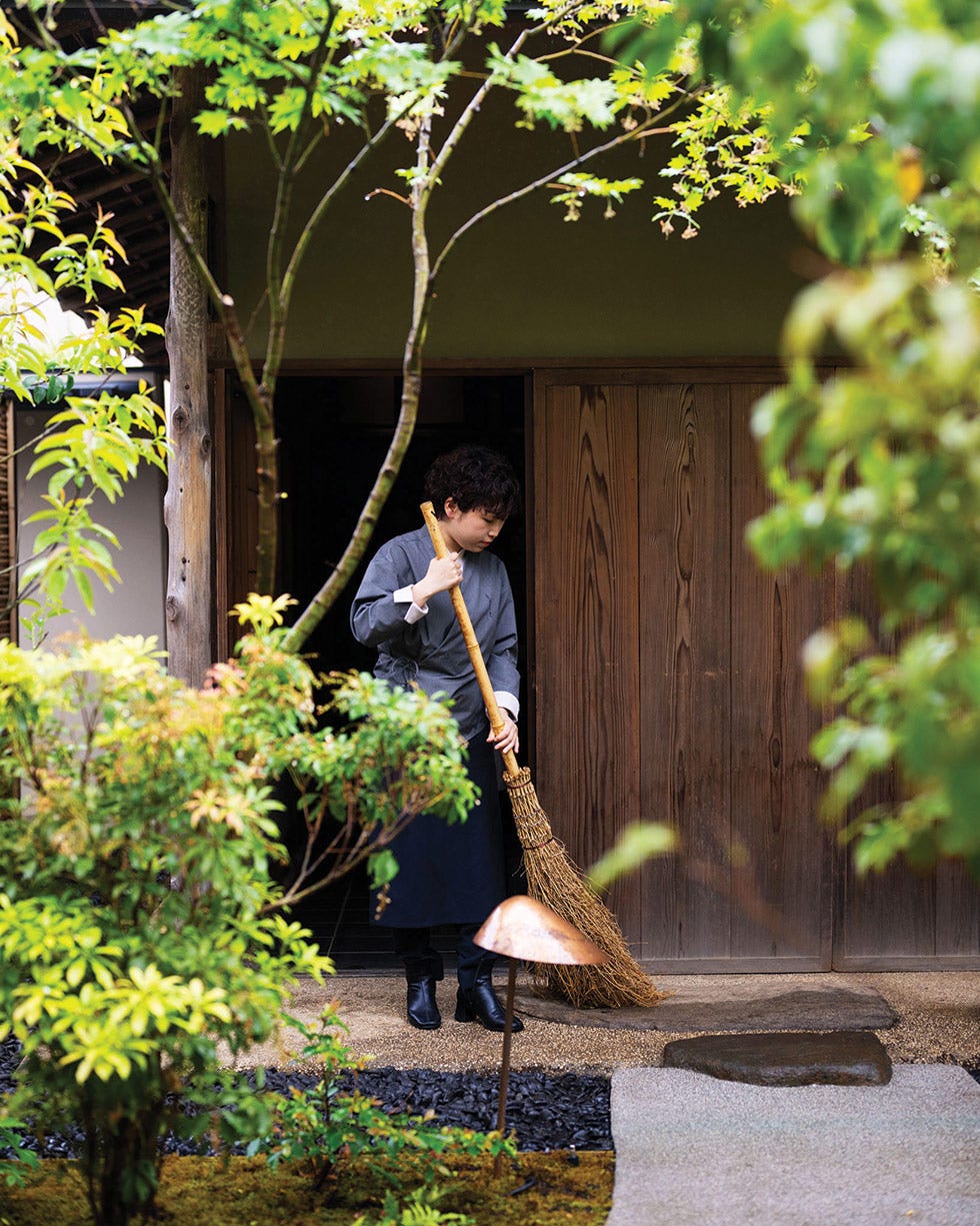 a person sweeping leaves in a japanese garden setting