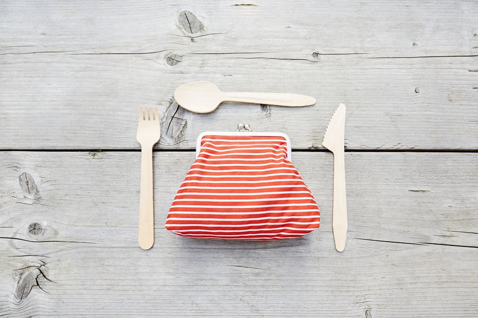 high angle view of a red white striped wallet and wooden cutlery on a table, symbol for food costs