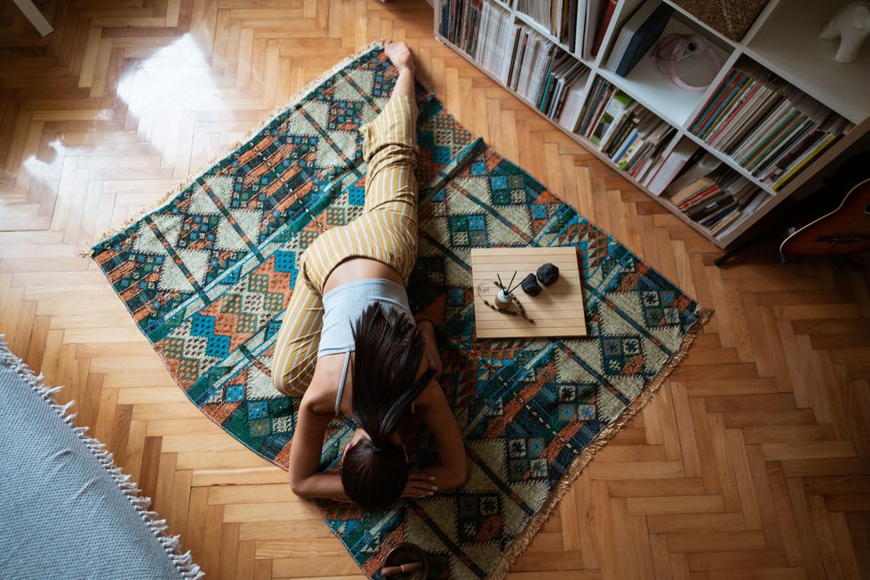 high angle view of a young woman in pigeon pose relaxing at home