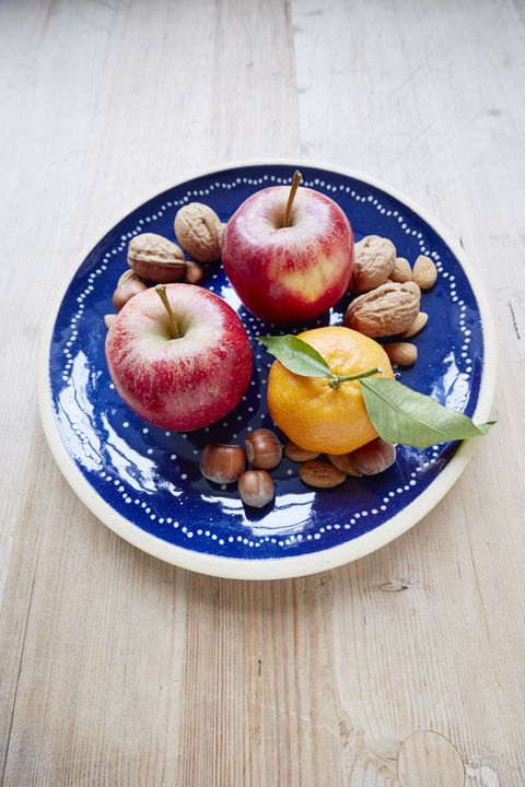High angle view of apples, mixed nuts and mandarin on plate