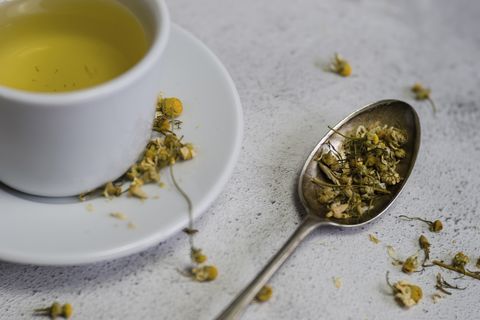 high angle view of chamomile tea in cup by spoon on table