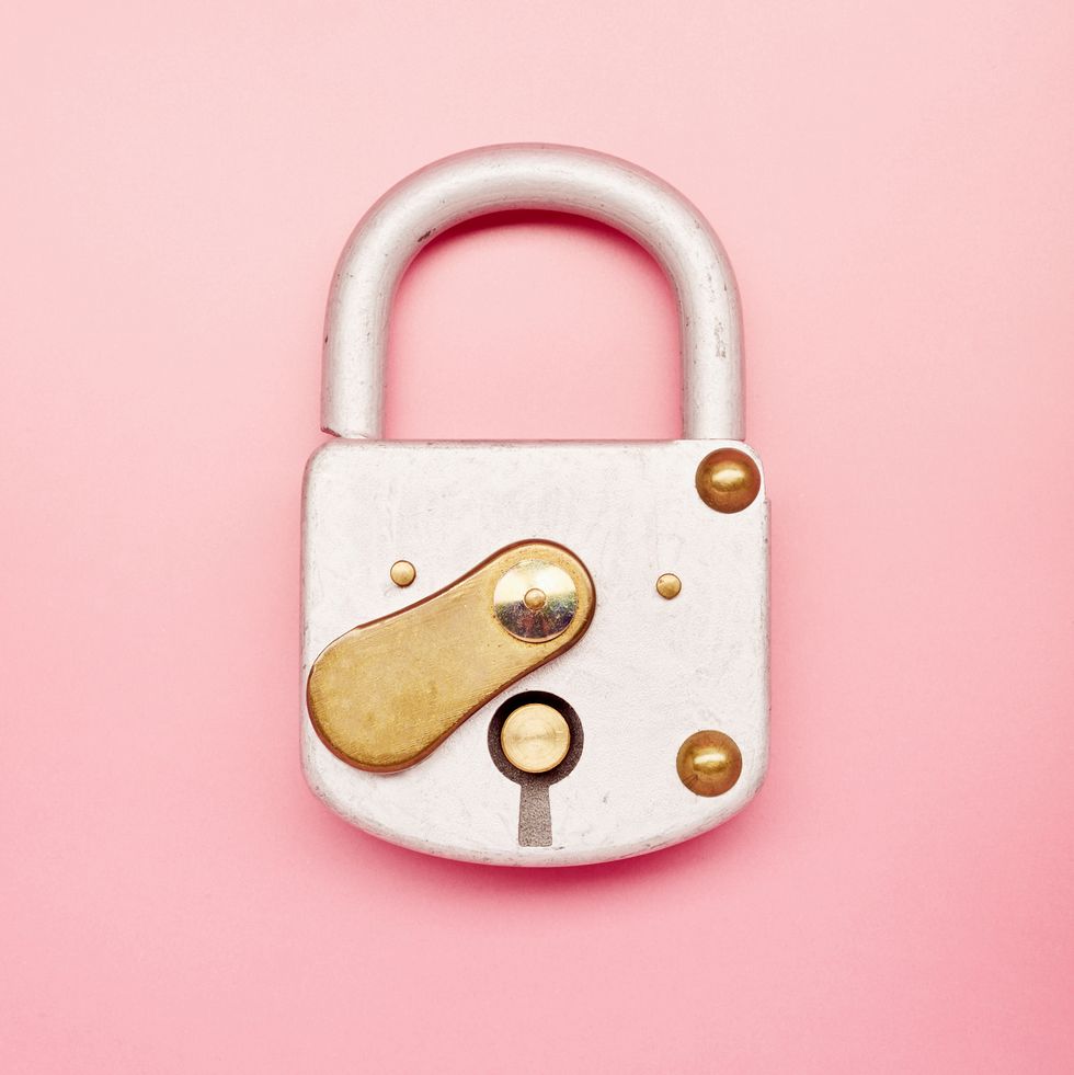high angle view of closed metal padlock on pink background