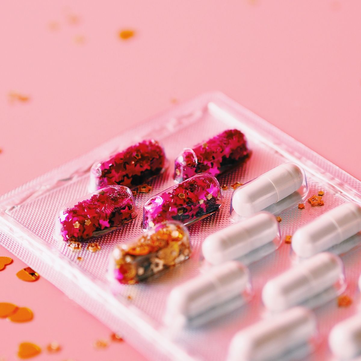 High Angle View Of Confetti With Capsules In Blister Packs Over Pink Background