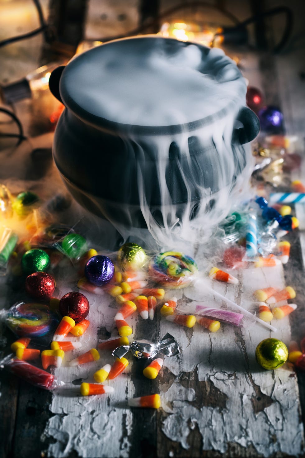 High Angle View Of Cooking Pot With Smoke Amidst Scattered Candies On Table During Halloween