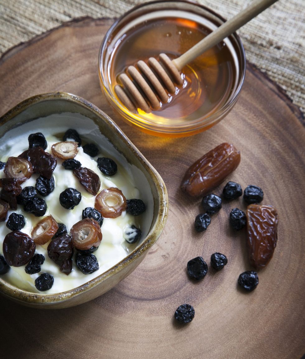 high angle view of dried fruits in yogurt with honey on table