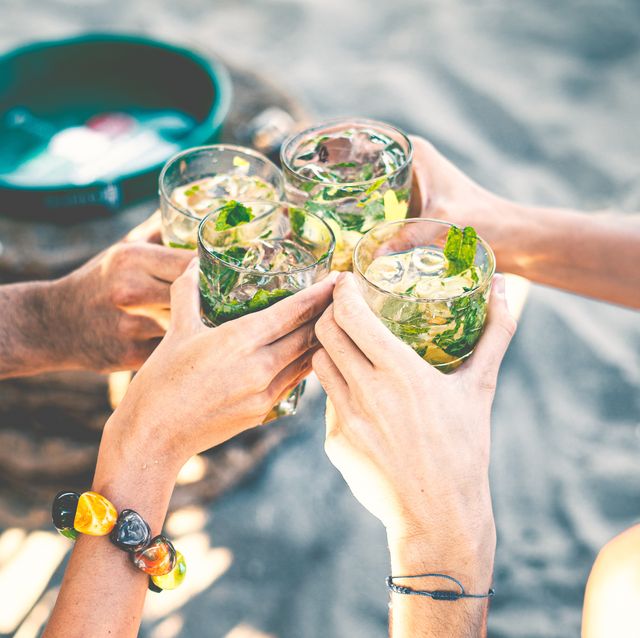 high angle view of group of people toasting holding glass with tropical  cocktails