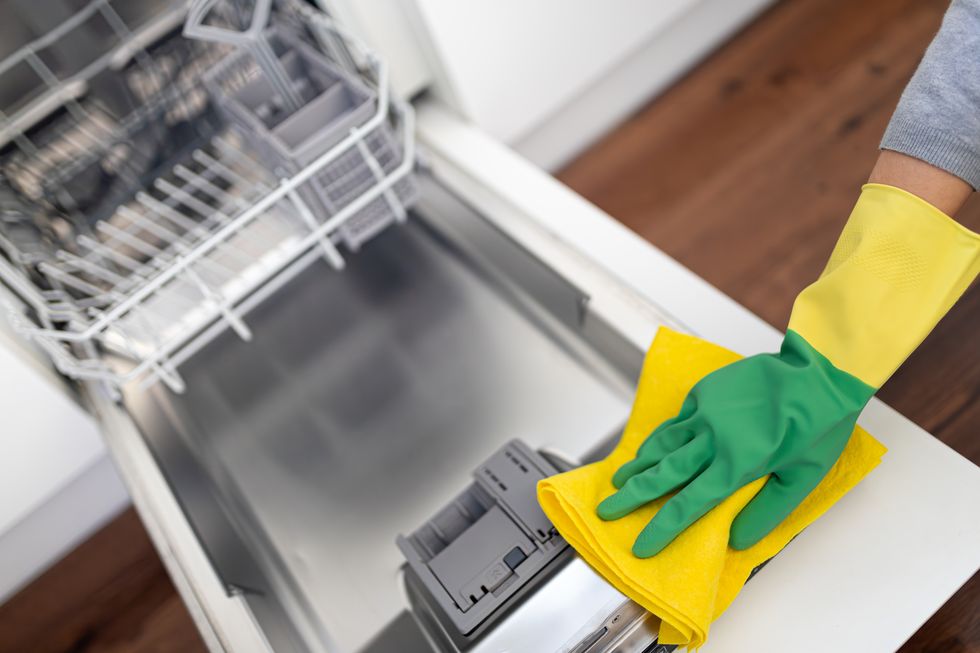 someone cleaning a dishwasher door while wearing gloves