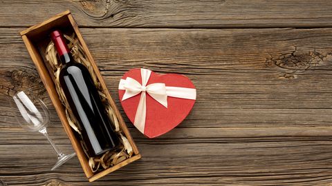 high angle view of heart shaped gift box with wine bottle on table