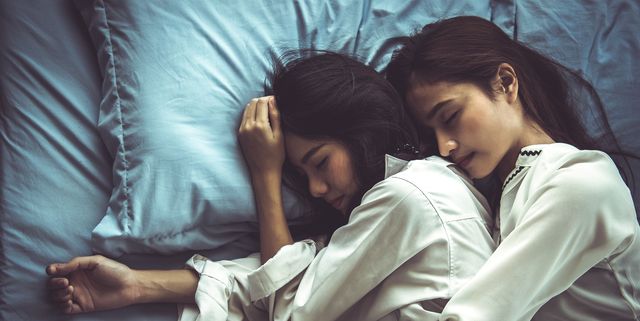 High Angle View Of Lesbian Couple Sleeping On Bed At Home