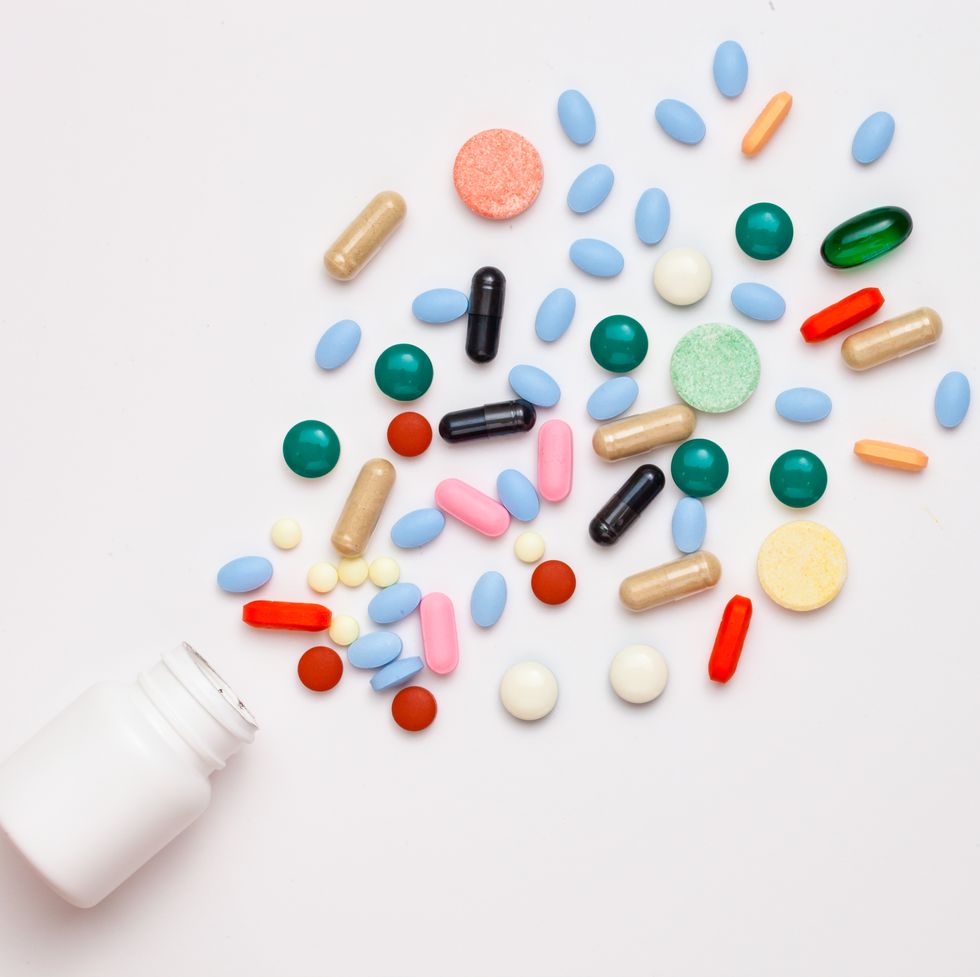 High Angle View Of Multi Colored Pills And Bottle Against White Background