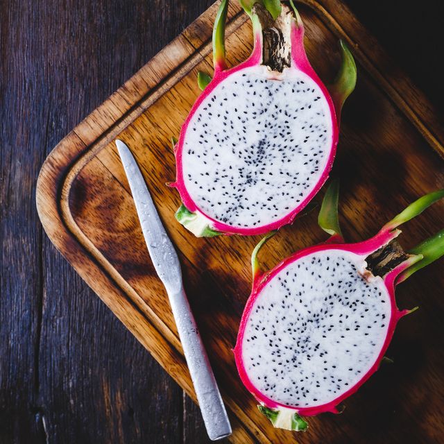 high angle view of pitaya with knife and cutting board on wooden table