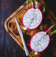 high angle view of pitaya with knife and cutting board on wooden table