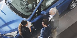 high angle view of saleswoman talking to customers at car showroom