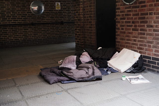 high angle view of sleeping bag on footpath by brick wall in city