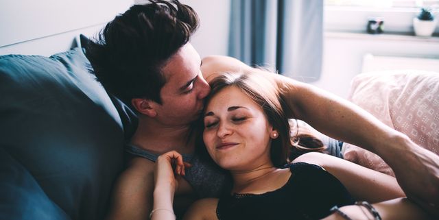 high angle view of smiling young man kissing woman sleeping on bed at home