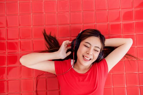 High Angle View Of Smiling Young Woman Listening To Music On Headphones