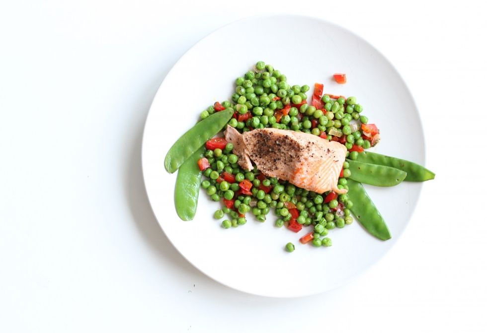 high angle view of steamed salmon with green peas in plate on table