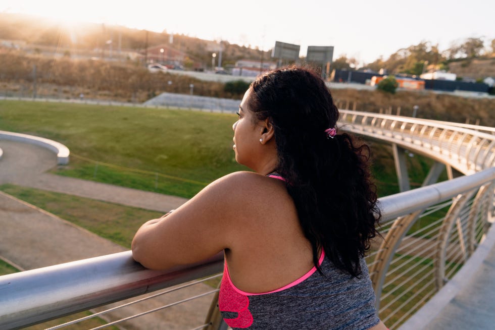 high angle view of thoughtful sportswoman leaning on railing