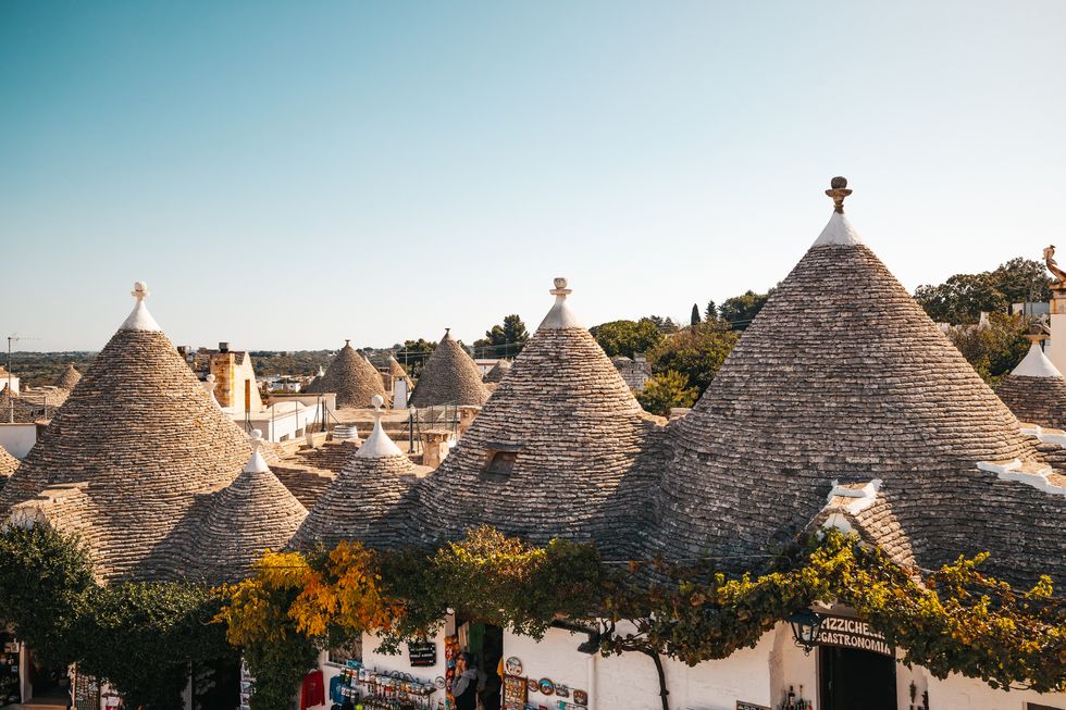 high angle view of trulli houses with conical roofs in a row in old town against clear sky during sunny day at alberobello