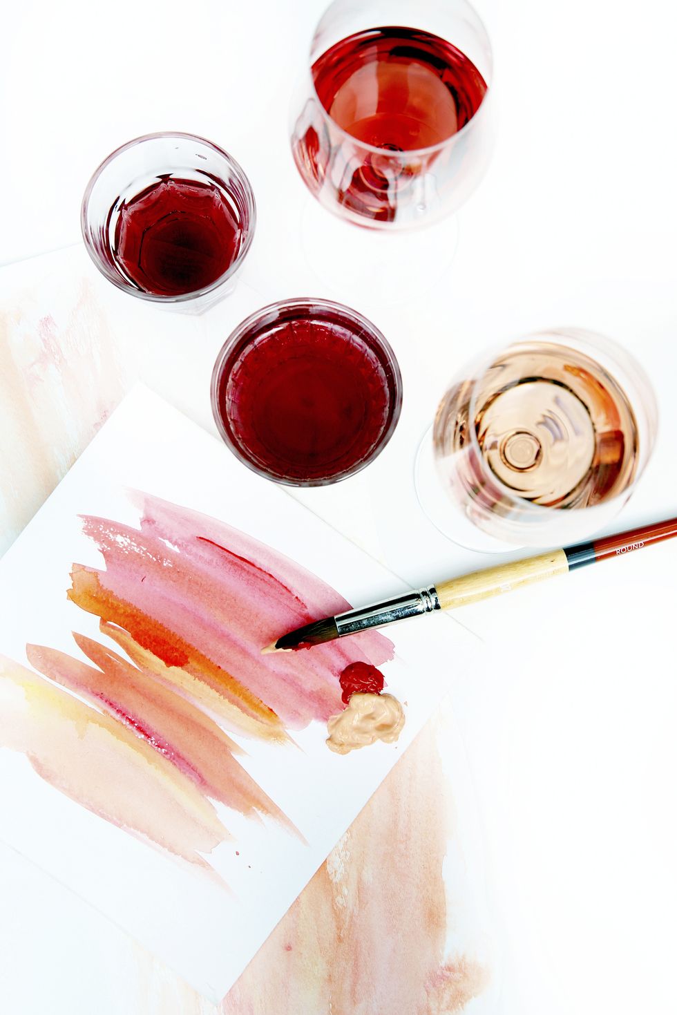 high angle view of watercolor paints with paper and paintbrush by drinks on table