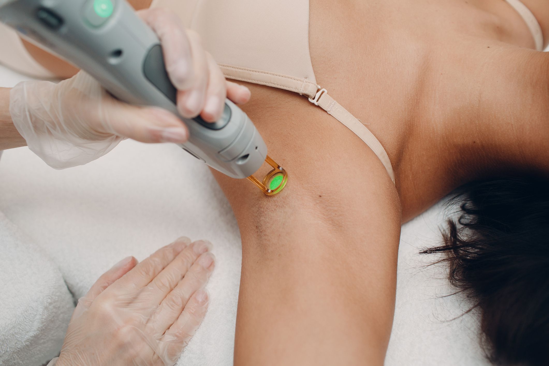 Close up of female beautician in sterile gloves using diode laser hair  removal machine while woman sitting on daybed. Esthetician preparing  equipment for epilation procedure. Stock Photo | Adobe Stock