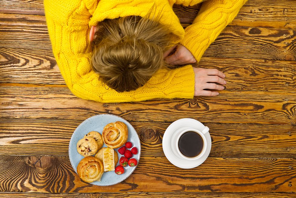 high angle view of woman sleeping by breakfast on table