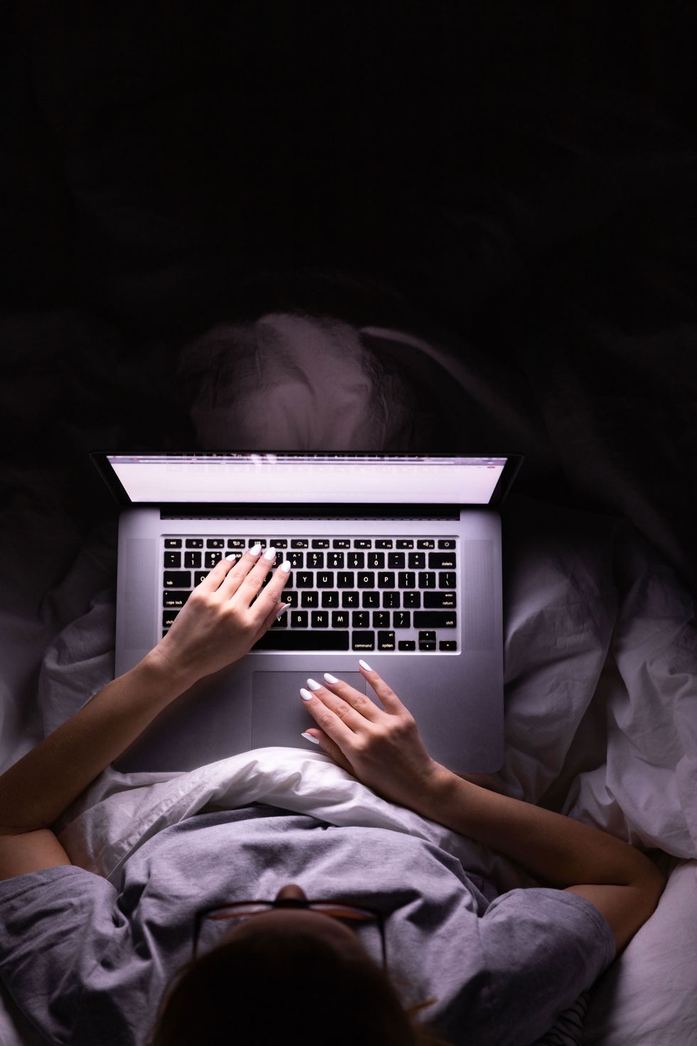 high angle view of woman using laptop while sitting on bed