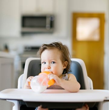 baby with sippy cup sitting in high chair