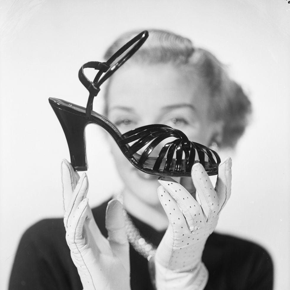 woman holding black 1950s ankle strap heels