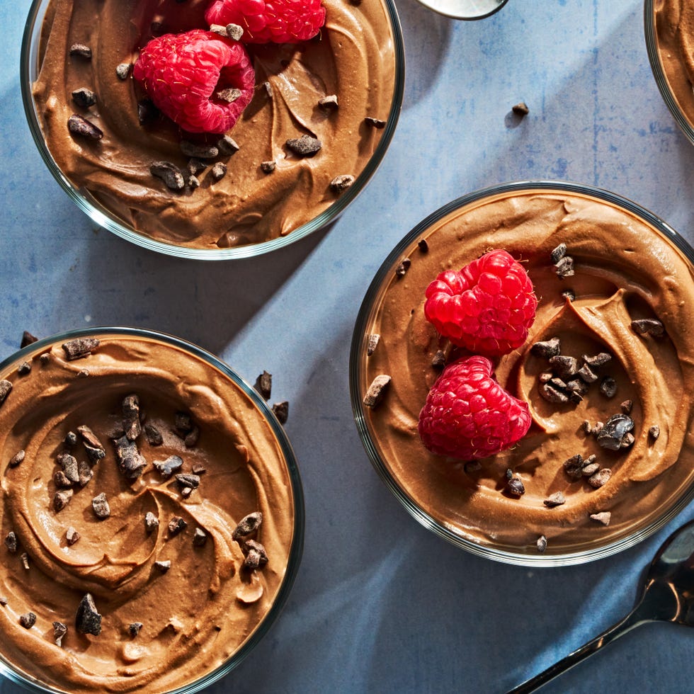 chocolate mousse in a cup topped with chocolate pieces and raspberries