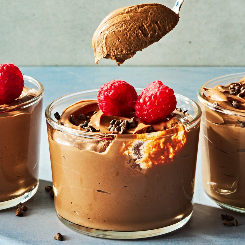 chocolate mousse in a cup topped with chocolate pieces and raspberries