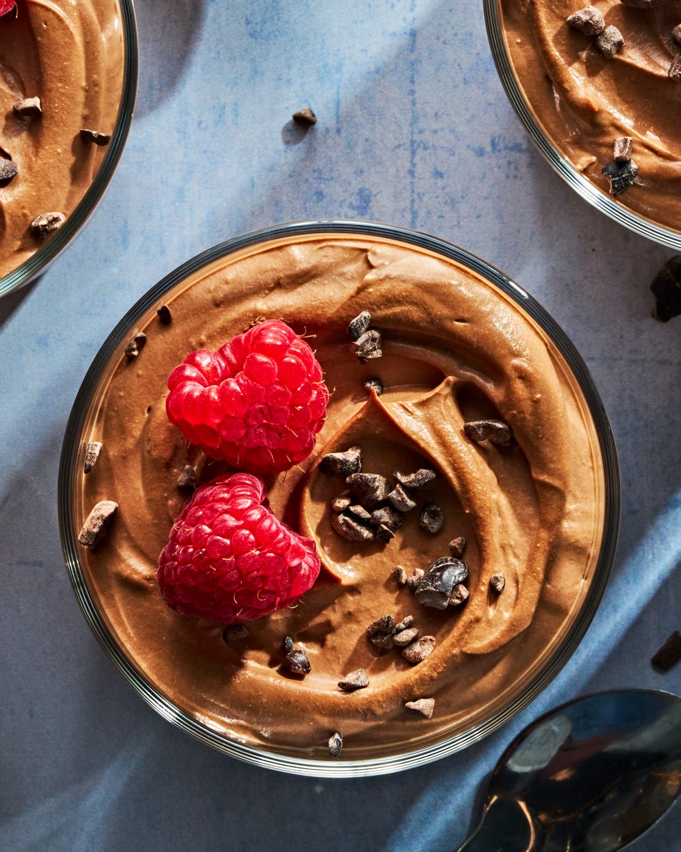 chocolate mousse in a cup topped with chocolate pieces and raspberries