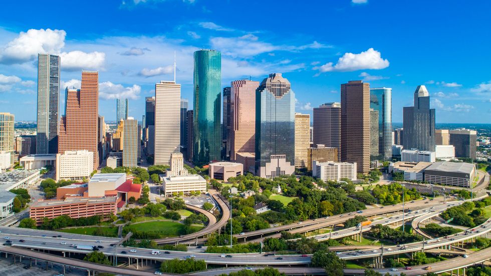 high quality aerial view of downtown houston skyline and freeway in texas, with commercial building in a blue sky day.