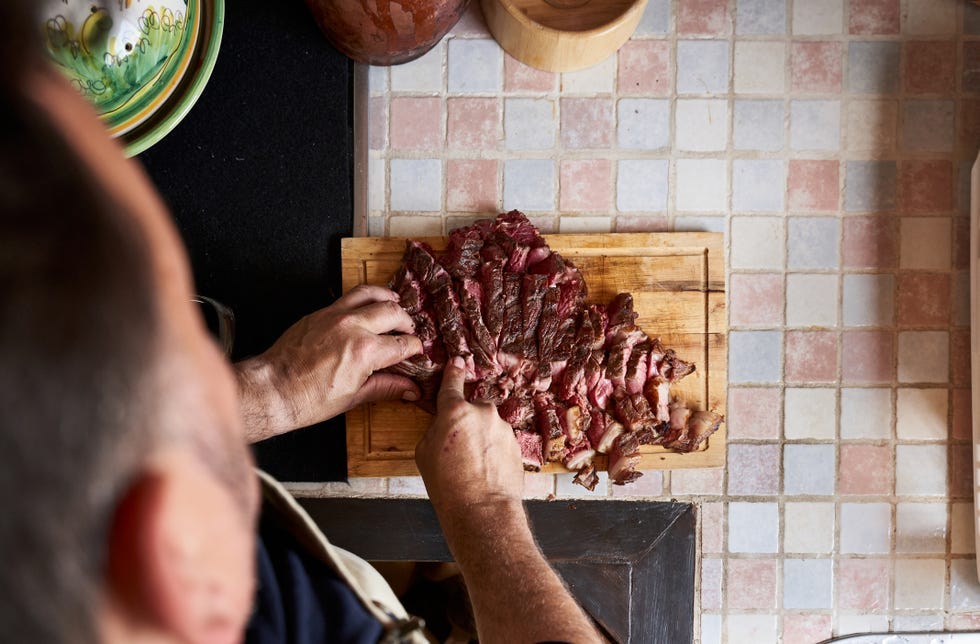 slicing cooked meat on a wooden cutting board