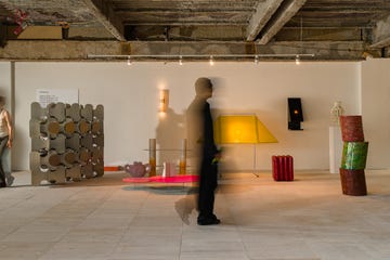 person walking through a room featuring installations curated by collectible, blurry because of camera exposure settings