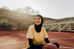 portrait of a smiling young woman with a hijab, ready to play some basketball