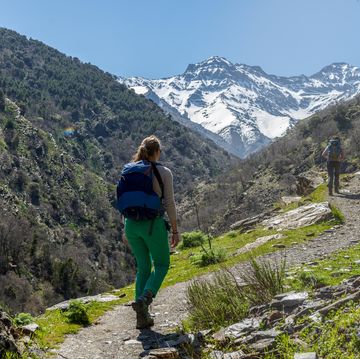 hiker on a hiking trail, behind sierra nevada, snowy mountains at granada, andalucia, spain