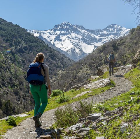hiker on a hiking trail, behind sierra nevada, snowy mountains at granada, andalucia, spain