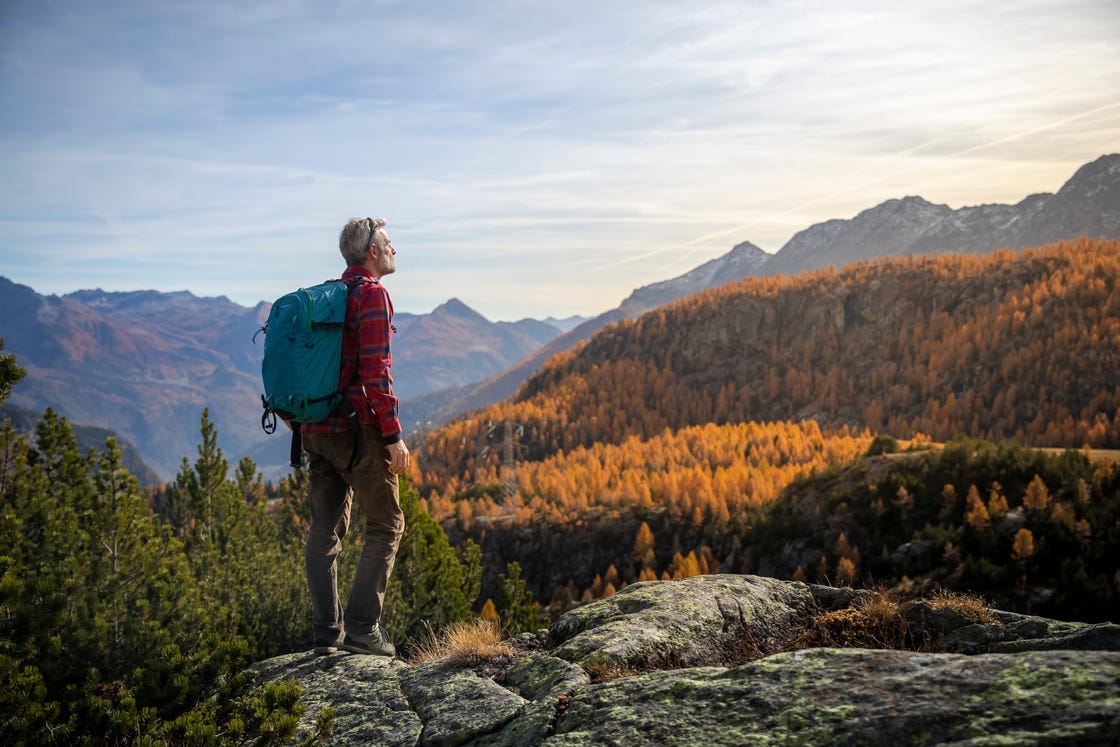 hiker standing in front of the mountain valley in autumn